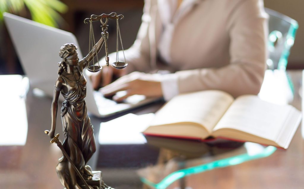 Lady justice with person typing in background